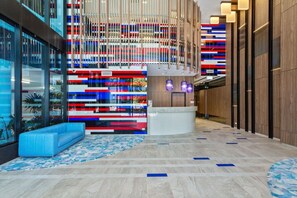 A modern lobby with a reception desk, seating area, and a colorful abstract wall. - Amazing 3 Brm Apt 6th Floor Hinterland Views (Broadbeach)