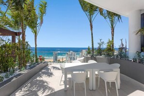 A terrace with a table and chairs, overlooking a beach and ocean. - Amazing 3 Brm Apt 6th Floor Hinterland Views (Broadbeach)