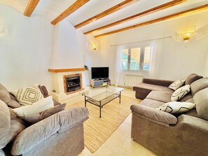 Ein Wohnzimmer mit Kamin, Sofa, Fernseher und einem großen Fenster.