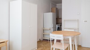 A compact kitchen with white cabinets, a wooden dining table, and a white chair. - Żelazna Classy Nest Apartment (Warszawa)