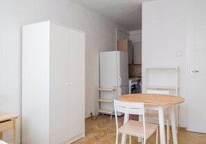 Uma cozinha compacta com armários brancos, uma mesa de jantar de madeira e uma cadeira branca.
