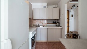 A compact kitchen with white cabinets, a sink, a stove, and a kettle. - Żelazna Classy Nest Apartment (Warszawa)