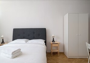 Quarto com cama, mesa de cabeceira com luminária, guarda-roupa e uma cadeira.