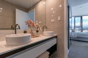 A modern bathroom with two sinks, a large mirror, and a view of a bedroom through a glass door. - L7 Stunning 2 Bedroom Apt Skyline Views (Broadbeach)