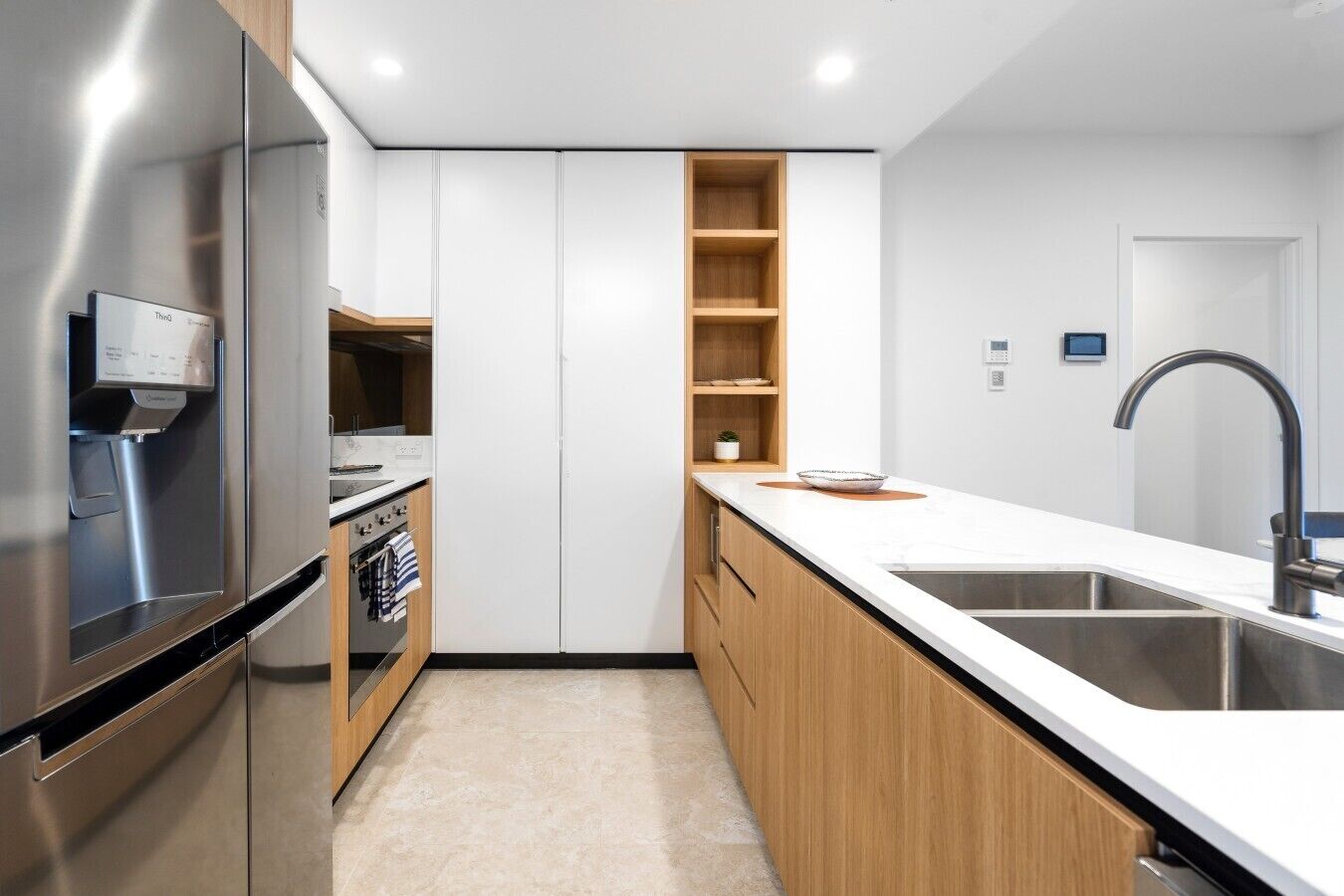 A modern kitchen with a stainless steel refrigerator, built-in oven, and a wooden countertop.
