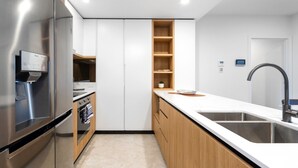 Une cuisine moderne dotée d’un réfrigérateur en acier inoxydable, d’un four encastré et d’un plan de travail en bois.
