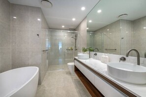 Ein modernes Badezimmer mit einer großzügigen freistehenden Badewanne, einer bodengleichen Dusche und einem langen Waschtisch mit zwei Waschbecken.