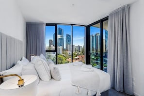 Ein modernes Hotelzimmer mit einem gewölbten Bett, großen Fenstern und Blick auf die Stadt.