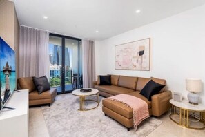 Ein modernes Wohnzimmer mit einer Couch, einem Hocker, einem Couchtisch und einem Gemälde an der Wand.