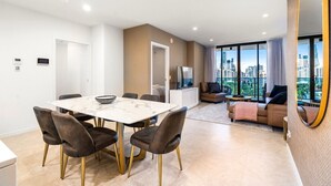Un appartement moderne comprenant un coin repas, un salon avec canapé et télévision, et un balcon offrant une vue sur la ville.