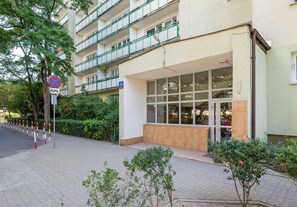 Un edificio de varios pisos con entrada a nivel de calle, un cartel de prohibido estacionar y un letrero azul con el número 29.