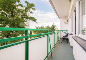 Un balcon avec une rambarde verte, une petite table et des chaises.