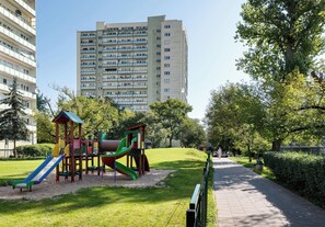 A playground with slides and climbing structures, surrounded by a park with a walking path and greenery. - Pole Mokotowskie Modern Nest Apartment (Warszawa)