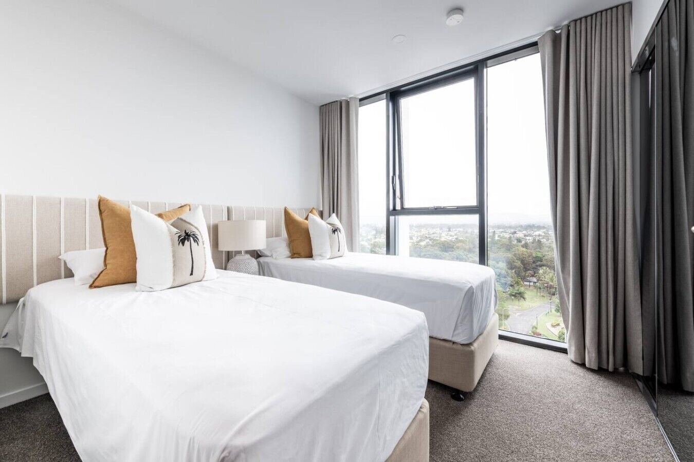 Ein Hotelzimmer mit zwei Betten, einem großen Fenster und Blick auf die Stadt.