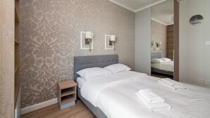 Ein Hotelzimmer mit einem Bett, einem Nachttisch, einem Spiegel und einer Wand mit ornamentalem Wandpapier.