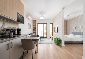 Eine moderne Küche mit Essbereich, ein Wohnzimmer mit Bett und Blick auf die Stadt durch die Fenster.