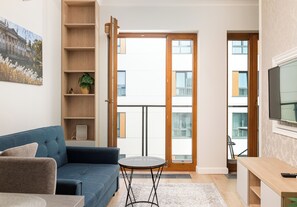 A modern living room with a blue sofa, a small round table, and a bookshelf. - Pawia Studio Centrum 75 (Warszawa)