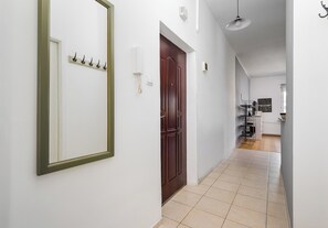 Un pasillo con una puerta de madera, un perchero y una pared blanca con un accesorio de iluminación.