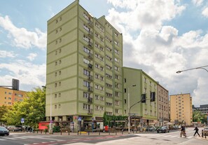 A multi-story building with a flat facade, numerous windows, and a pedestrian crossing in front. - Elektrownia Powiśle Homely Apartment (Warszawa)