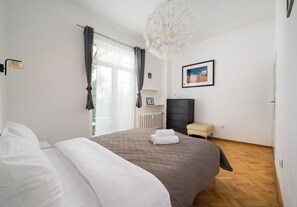 A hotel room with a large bed, a radiator, a small stool, and a picture on the wall. - Elektrownia Powiśle Homely Apartment (Warszawa)