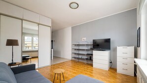 Un salon moderne avec un canapé, un téléviseur et un plancher en bois.
