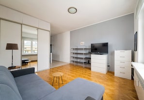 A modern living room with a sofa, a TV, and a wooden floor. - Elektrownia Powiśle Homely Apartment (Warszawa)
