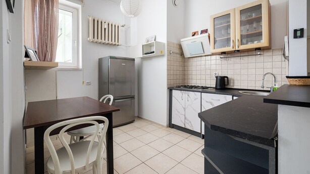 Une cuisine compacte équipée d’un réfrigérateur, d’une cuisinière et d’un petit coin repas avec une table et des chaises.