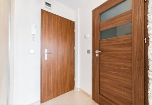 Zwei Holztüren mit modernem Design, eine mit Glasfenster, und ein Lichtschalter an der Wand.