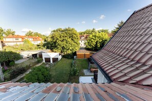 A residential area with a view of a house with a red-tiled roof, a grassy yard, and a large tree. - Gdańsk Wrzeszcz Comfort Apartment (Gdańsk)