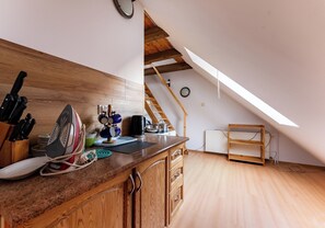 Eine Küche mit Holzausstattung, Arbeitsplatte und diversen Küchengeräten. Eine Holztreppe führt zu einer oberen Ebene.