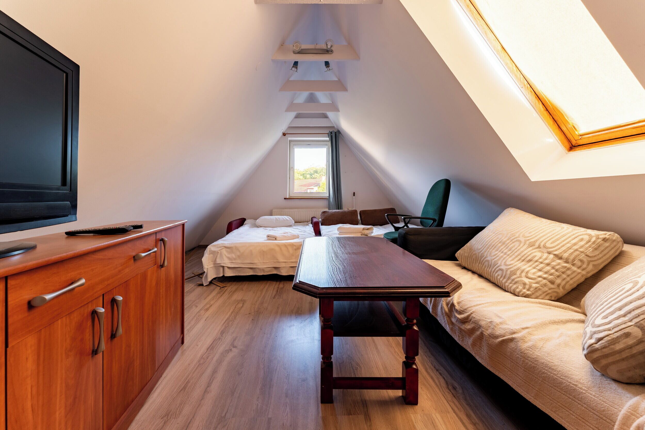 Une petite pièce confortable, avec un lit, une table en bois, un téléviseur et une fenêtre.