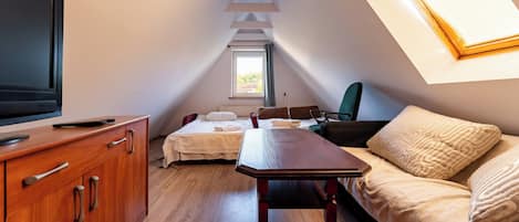 Una habitación pequeña y acogedora con cama, una mesa de madera, televisión y ventana.