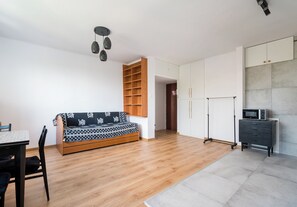 Ein moderner Wohnraum mit Sofa, Esstisch, Stühlen, Küchenzeile und Kleiderschrank.