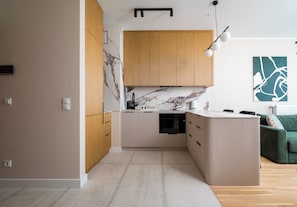 Eine moderne Küche mit eingebautem Ofen, Holzschränken und einer Marmor-Spritzschutzwand.