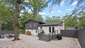 A two-story house with a covered outdoor area, a gravel driveway, and a wooden fence.