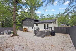 A two-story house with a covered outdoor area, a gravel driveway, and a wooden fence.
