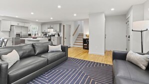 A modern living room with a grey sofa, a coffee table, and a patterned rug.