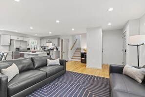 A modern living room with a grey sofa, a coffee table, and a patterned rug.