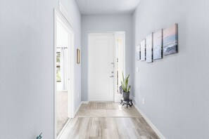 Un passadís amb una porta blanca, una petita catifa i una planta en test.