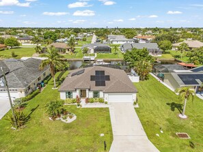 A residential area with houses, a central driveway, and a body of water. - Cape Coral Villa with Heated Pool & Dock (Cape Coral)