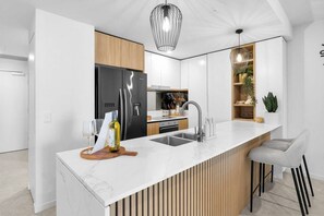 Eine moderne Küche mit Marmorarbeitsplatte, Edelstahlgeräten und einer Wand mit Holzverkleidung.