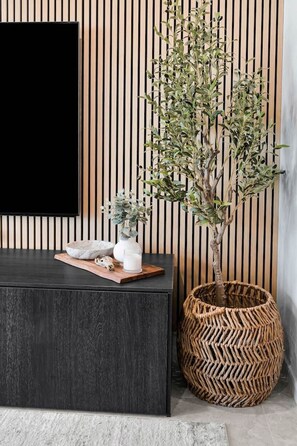 A modern interior with a dark wood console table, a woven basket, and a potted plant against a striped wall. - Lv 14 Stunning 2 Brm Apt with Skyline Views (Broadbeach)