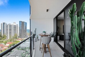 Ein Balkon mit Tisch und Stühlen, einer Topfpflanze und einem großen Kaktus.