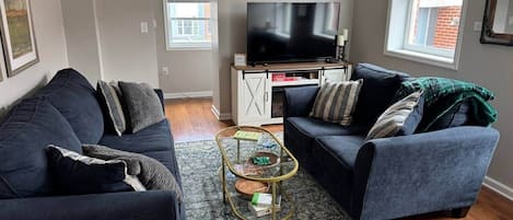 Una sala de estar con dos sofás, una mesa de centro y un televisor de pantalla plana.