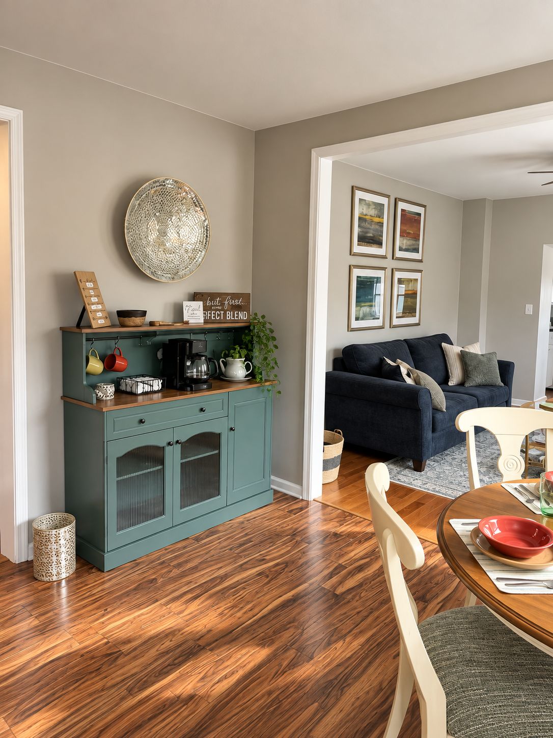 A living room with a teal cabinet, a dark blue sofa, and a dining area with a wooden table and chairs.