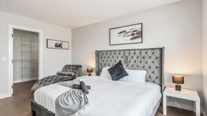 Una camera da letto con un letto, due comodini, una sedia, un armadio e due quadri appesi al muro.