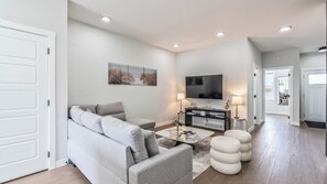 Ein modernes Wohnzimmer mit einem grauen Sofa, einem Flachbildfernseher und einem Couchtisch.