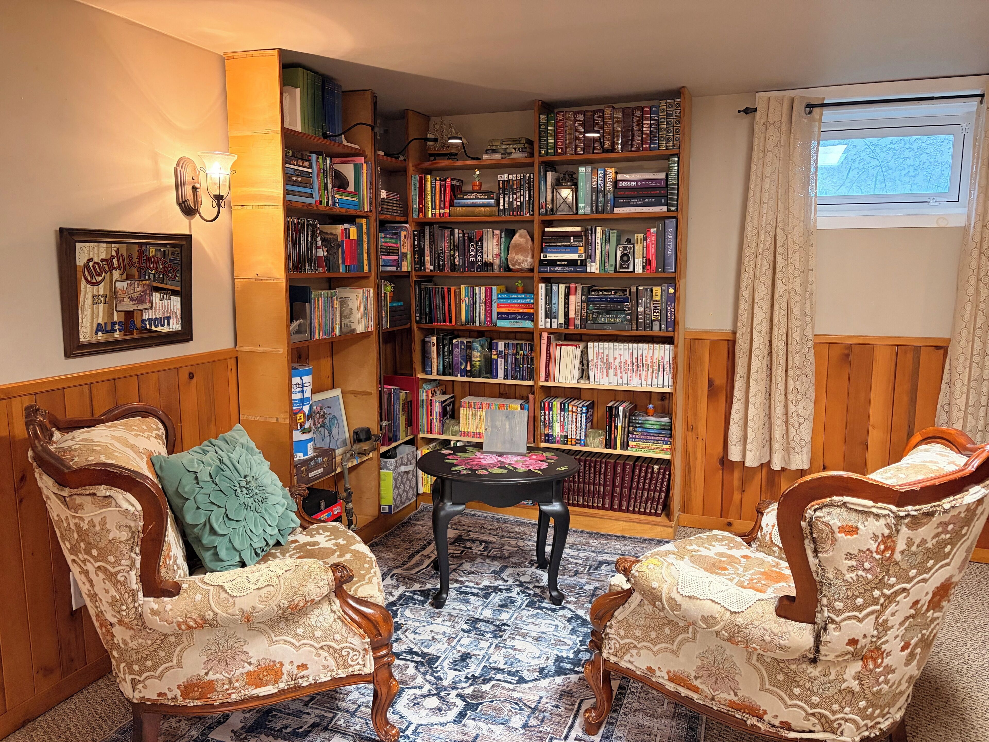 A cozy reading nook with two upholstered chairs, a small table, and a bookshelf filled with books.