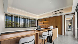 A modern kitchen with a wooden countertop, bar stools, and a laptop.