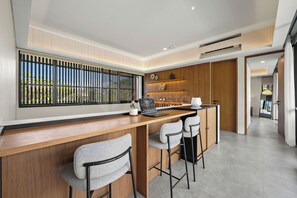 A modern kitchen with a wooden countertop, bar stools, and a laptop.